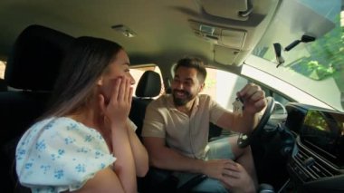 Mutlu bir aile emlak satın alıyor, gülümsüyor, beyaz bir kadın kadın, erkek kocası tarafından şaşırtılıyor, ev anahtarlarını gösteriyor, ev kiralıyor, ev kiralıyor, araba içinde parmak işareti yapıyor.