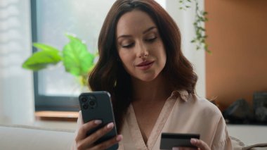 Mutlu gülümseyen müşteri müşterisi kadın alıcı Kafkasyalı kız cep telefonu uygulaması ile alışveriş yapıyor online satın alma ürünleri siparişi ecommerce ev kadınından kredi kartıyla internet alışverişi yapıyor