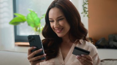 Mutlu gülümseyen müşteri müşterisi kadın alıcı Kafkasyalı kız cep telefonu uygulaması ile alışveriş yapıyor online satın alma ürünleri siparişi ecommerce ev kadınından kredi kartıyla internet alışverişi yapıyor