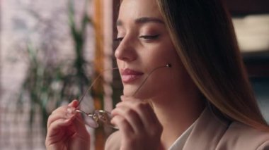 Güzel, kendine güvenen, beyaz, pozitif iş kadını, bayan iş kadını, girişimci, gözlük takan gözlüklü, optometri görünümlü kamerayı takıp ofisin içinde gülümsüyor.