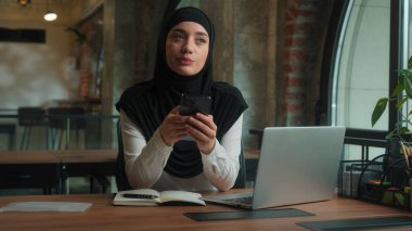 Düşünceli Müslüman kadın işkadını işveren, İslami tesettüre sahip, tesettüre girmiş, iş kadını, kadın yönetici, iş yeri çalışanı, cep telefonu cihazı bağımlısı, akıllı telefon internetine mesaj yazmayı düşün.