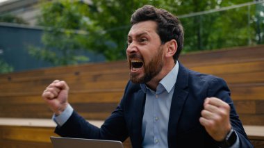 Sinirli, kızgın, Kafkas işadamı öfkeli iş adamı uzak bir laptopta çalışıyor erkek adam dışarıda konuşuyor cep telefonuyla konuşuyor kavga ediyor kavga çığlıkları atıyor cep telefonunu atıyor.