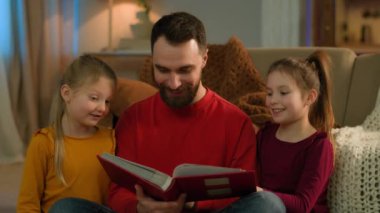 Kafkasyalı baba, ebeveyn, bebek bakıcısı, mutlu aile, küçük çocuklar, kızlar, hafta sonları evde sevgili babalar kitap okuyor, masal kitapları okuyor, çocuklar, babalık fotoğrafları izliyorlar.