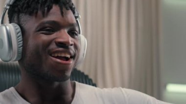 Beyaz fütürizm stüdyosundaki aktif Afrikalı Amerikalı etnik adam. Kulaklık takan, fütüristik erkek. Kulaklık takan, müzik dinleyen.