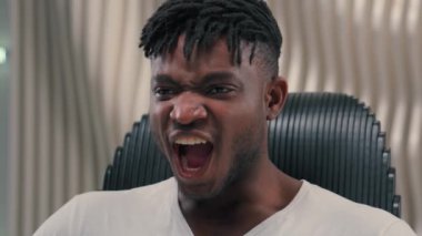 Öfkeli, öfkeli, sinirli, olumsuz ruh hali Afro-Amerikan, etnik siber adam, beyaz, fütürizm stüdyosu, kapalı bir yerde erkek, bağırıyor, öfke, rahatsız edici, fütüristik bir sorun var.