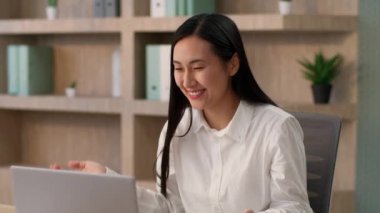 Neşeli gülümseyen Çinli iş kadını Asyalı kız işçi mutlu Koreli Japon iş kadını dizüstü bilgisayarla konuşuyor internetteki konferans görüntülü görüşme web kamerası konferansı ofisinde