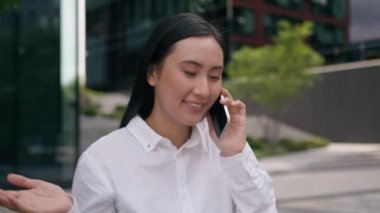 Neşeli, mutlu, Asyalı, Çinli bir Japon kadının cep telefonuyla konuşması, akıllı cep telefonu, gülümseyen bir kız. Konuşan bir kız. İş kadını.