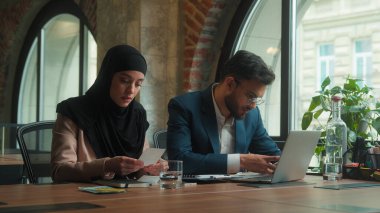 Erkek, kadın, Arap, erkek, kadın, tesettürlü, erkek, erkek, iş kadını, iki mutlu iş arkadaşı, yöneticiler pazarlama grafiklerini analiz eden, dizüstü bilgisayarda yazı yazan iki iş arkadaşı.