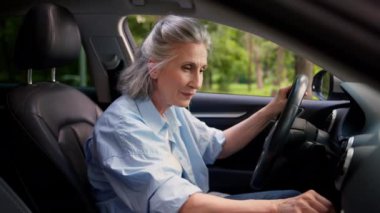 Neşeli, Kafkasyalı, yaşlı, yaşlı kadın, kiralama servisi müşterisi araba satıcısı, modern otomobilin içindeki olgun kadın araba sürücüsü müzik radyosunu aç ve ses sistemi ses dansının tadını çıkar.
