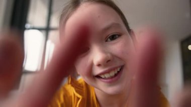 Webcam POV kaygısız, neşeli, beyaz kız öğrenci kız, zoom ekran cihazı AR çocuk cep telefonu dokunmatik ekranlı parmak ekranı kullanıyor.