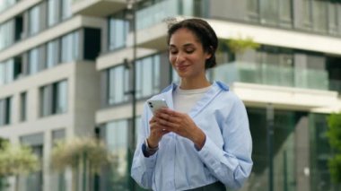 Mutlu bir şekilde gülümseyen iş kadını, Afrikalı Amerikalı iş kadını, ofis kadını, şehir merkezinde cep telefonuyla internet üzerinden akıllı telefon sohbeti yapan bir kadın.