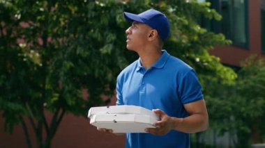 Afrika kökenli Amerikalı kurye elinde pizza paketi, elinde hazır yiyecek, kafede çalışan erkek karton kutuların bulunduğu adrese gidiyor.