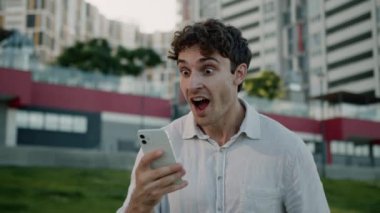 Mutlu Kafkasyalı adam cep telefonu tutuyor. İyi haber. Kazanan iyi haber. Başarılı erkek iş adamı başarısını kutluyor.