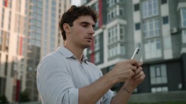 Ciddi bir Kafkasyalı elinde cep telefonu, akıllı sohbet internet uygulaması, dalgın işveren, şehir iş adamı, açık hava sosyal medya sitelerinde cep telefonu ağı mesajları yazıyor.