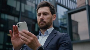 Kafkas erkek işadamı işvereni yetişkin adam akıllı telefon kullanıcısı internet bağlantısı cep telefonu aygıtı bağımlısı açık havada cep telefonu ekranı yazıcı şehirdeki SMS çevrimiçi uygulama alışverişi