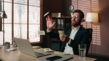 Mutluluktan havalara uçuyor, zenginliği kutluyor, para ödülü kazanıyor, para kazanıyor, Kafkasyalı orta yaşlı iş adamı, ofiste çalışan erkek işveren, hava yatırımlarına dolar atıyor.