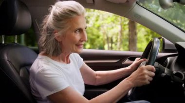 Meraklı beyaz kadın, son sınıf öğrencisi, olgun, yaşlı kadın, kiralık araba şoförü, modern elektrikli otomobil sürücüsü, direksiyonlu, motor sürücüsü, şanzıman sürücüsü.