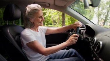 Heyecanlı, aşırı mutlu, beyaz, gülümseyen kadın yaşlı, yaşlı, yaşlı kadın, kiralık araba, modern elektrikli otomobil, hayran olunan salon direksiyonu, yeni nakliye aracı.