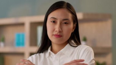 Yakın plan başarılı Japon iş kadını gülümseyen Asyalı bayan iş kadını Koreli öğrenci öğretmen kamera karşısında ofis içinde poz veriyor.