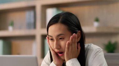 Çok şaşıran Asyalı iş kadını kadın Koreli etnik iş kadını ofis çalışanı dizüstü bilgisayarı görünce şaşırdı ve şaşırdı.