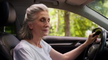 Gülümseyen, emekli, Kafkasyalı, mutlu, yaşlı, emekli kadın, kadın, araba şoförü, arabada oturan, kameraya gülümseyen, el ele tutuşan, direksiyon sallayan, emekliliğe giden kadın.