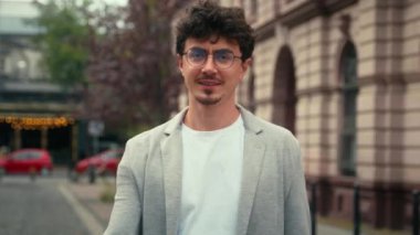 Mutlu gülümseyen, mutlu, mutlu, memnun, İspanyol bir adam, şehir dışında, dışarıda kameraya bakıyor, gülümsüyor, el hareketi yapıyor.