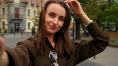 Web kameralı selfie fotoğraf makinesi elinde cep telefonu kayıtları video video bloğu etkisi gülümseyen poz veren beyaz kadın öpücükler gönderen açık hava modası