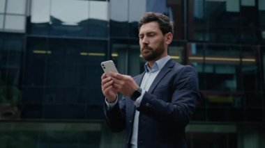 Kafkasyalı bir adam akıllı telefon erkek girişimci kullanıyor. Şehir iş adamlarının internet bağlantılarını kuruyor. Dışarıdaki internet üzerinden mesaj yazıyor.