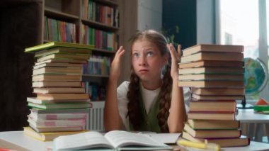 Sıkılmış, sinirli, küçük beyaz kız çocuğu okul çocuğu okul çocuğu okul kitapları çok fazla ev ödevi çok fazla eğitim sorunları kapalı kütüphanede bitkinlik.