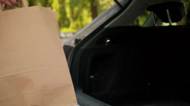 Tanımlanamayan Kafkasyalı üst düzey müşteri bayan yaşlı alışverişçi kadın alıcı paketleri araba bagajına koyuyor elektrikli araba alışverişi yapıyor.