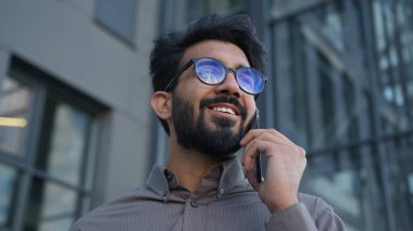 Mutlu gülümseyen Arap Hintli adam başarılı bir iş adamı. Etnik adam cep telefonundan konuşuyor. Erkek işverenle sohbet ediyor.