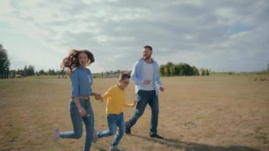 Mutluluktan kahkahalar atan mutlu bir aile dışarı koşuyor, beyaz bakıcı anne, kadın, baba, el ele tutuşan erkek, çocuk, çocuk, çocuk, çocuk, okul bahçesinde birlikte koşuyorlar. Çocuk Esirgeme Kurumu