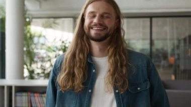 Ofiste, üniversitede, üniversite kütüphanesinde, beyaz erkek, işadamı, hippi öğrenci kameraya bakıp gülen neşe şakası yaparken çekilmiş bir portre.