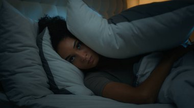 Gürültücü komşular rahatsız edici Afro-Amerikan kadın gece yatağında uzanan karanlık yatak odasında uykusuzluk çeken uykusuz, öfkeli kız gürültüyle kulaklarını yastıkla kapatarak uyumaya çalışıyor.