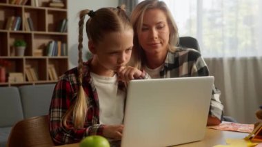 Odaklanmış Kafkasyalı kız çocuğu öğrenici kız öğrenci e-öğrenici kız liseli kız öğrenci ev eğitiminde dizüstü bilgisayar çalışıyor anne-baba, anne-baba, kadın kadına nafaka öğretmesine yardım ediyor.