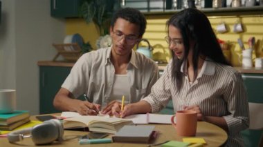 Ev mutfağında birlikte çalışan çok ırklı kız çocuğu Afro-Amerikan lise öğrencisi kadın mutlu genç erkek yazmayı öğreniyor arkadaşlar beşlik takım çalışması sınavı eğitimi veriyor.
