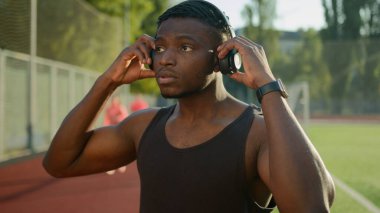Afrikalı Amerikalı hippi sporcu kulaklık takıyor. Açık havada erkek sporcu dalgın kas sporu sporcusu sağlıklı yaşam tarzı sporu eğitimi için Smart twatch 'te müzik listesi dinliyor.
