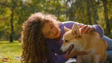 Beyaz mutlu kız çimenlerde altın yavru köpekle oynuyor yaz haftasonu kadın hayvan eğitmeni arkadaş evcil hayvan sever şehir parkında sevimli küçük köpek pembroke galsh corgi