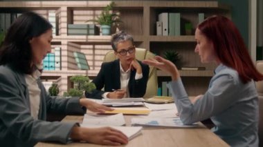 Takım çalışması, Kafkasyalı liderin Asyalı işçilere brifing vermesi, iş arkadaşlarının iş ortaklarıyla görüşmesi, iş kadınlarının iç mekanda iş birliği yapması.