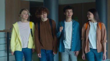 Dört beyaz öğrenci gülümsüyor koridorda yürüyor iletişim kuruyor erkek öğrencilerle konuşuyor kadın çalışmaları öğreniyor kadınların yürüdüğü erkekler kolejde birlikte yürüyorlar