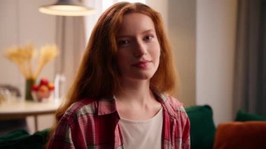 Portre mutlu, şirin, güzel, beyaz, güler yüzlü, kızıl saçlı, kadın daire içinde rahatlamış, Avrupalı bir bayan gülümsüyor, kameraya bakıyor, sağlıklı, sigorta kredisi teslimatına bakıyor.