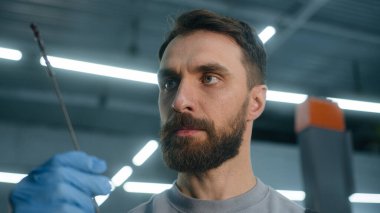 Profesyonel oto tamircisi Kafkasyalı tamirci oto tamirhanesinde çalışan erkek araba tamircisinde motor yağı yakıt seviyesini kontrol etmek için özel bir alet tutuyor.