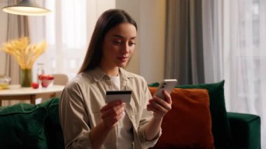 İnternetten internet üzerinden alışveriş yapan beyaz kadın banka hesabı satın alıyor. Kredi kartıyla cep telefonu kullanıyor. Banka kartlarını öpüyor.