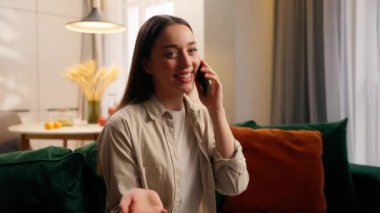 Gülümseyen Kafkasyalı kadın cep telefonu konuşmaktan mutlu. Arkadaşlarıyla sohbet ediyor. Kanepede oturan aile kızıyla haberleri paylaşıyor.