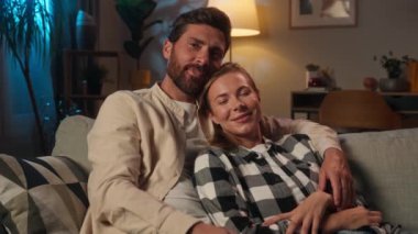 Aşk çifti Kafkas aile erkeği karı koca kanepede dinlenir akşam evde romantik hafta sonları sevecen kız arkadaş TV kanallarını değiştirip film izleyerek sarılır.