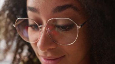 Kapalı yüzlü Afro-Amerikan kadın etnik kız öğrenci kız öğrenci üniversitede kapalı alanda iş kadını gülümsemesi odaklanmış, kapalı alanda gözlük takan mutlu bir vesikalık.