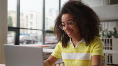 Mutlu Afrika kökenli Amerikalı kız öğrenci üniversite akademisi bilgisayarını kapat bilgisayarla bilgisayarını bitir ve online ders çalış.