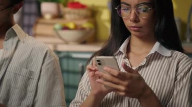 Afro-Amerikan Hintli öğrenciler üzgün çok ırklı çiftler kadın genci görmezden geliyorlar erkek gen z erkek ev mutfağında akıllı telefonlara bakıyorlar cihaz bağımlısı oynuyorlar cep telefonları kullanıyorlar sosyal medya alışverişi yapıyorlar