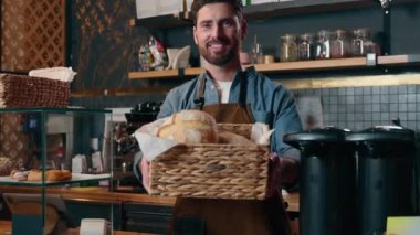 Gülümseyen Kafkasyalı garson adam yemek sepeti baristasını müşteriye sunuyor. Kafeteryada taze ekmek pastanesi ikram ediyor. Küçük işletme kafeteryasında iş adamı, kahve dükkanında çalışıyor.