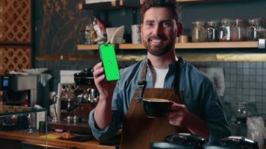 Kafkas asıllı bir adam, barista küçük işletme girişimcisi, cep telefonu yeşil ekran akıllı telefon uygulaması uygulayan Kafe çalışanı, kahve bardağı restoranını online uygulama teknolojisi ile işletiyor.